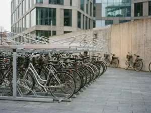 Fahrräder in modernem Stahlständer vor einem Bürogebäude bei bedecktem Tageslicht.